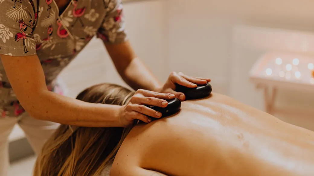 Kỹ thuật viên spa xoa bóp bằng đá nóng cho khách