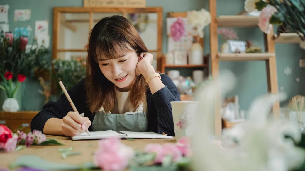 Chủ cửa hàng nhỏ xem sổ sách kế toán trên bàn làm việc