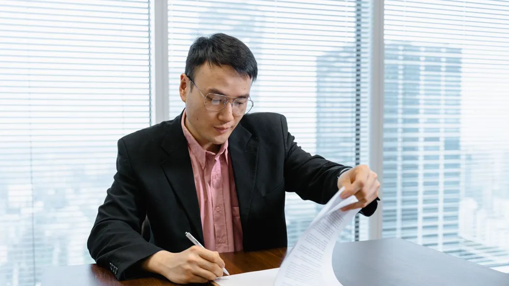 Người đàn ông mặc vest ký giấy tờ trong văn phòng cao tầng, minh họa thủ tục chuyển hộ kinh doanh thành công ty