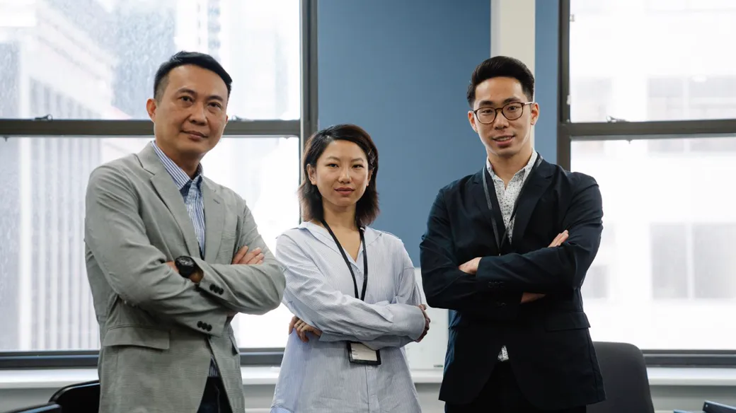 Ba người mặc trang phục công sở khoanh tay đứng trong văn phòng, minh họa các thành viên góp vốn công ty