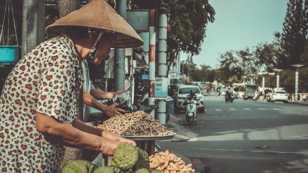 Người bán hàng đội nón lá bày nông sản trên vỉa hè, ví dụ hộ kinh doanh nhỏ tại Biên Hòa