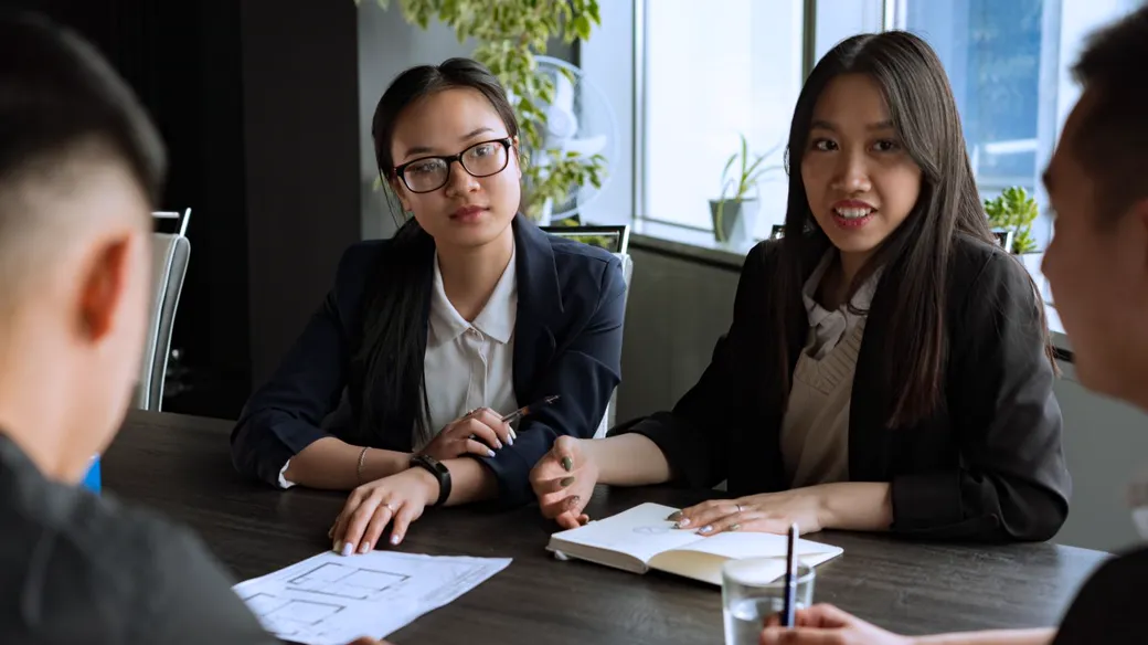 Ba người quanh bàn với giấy tờ và sổ sách, trao đổi phạm vi công việc kế toán hộ kinh doanh